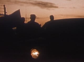 Three figures in silhouette against an orange dusk sky
