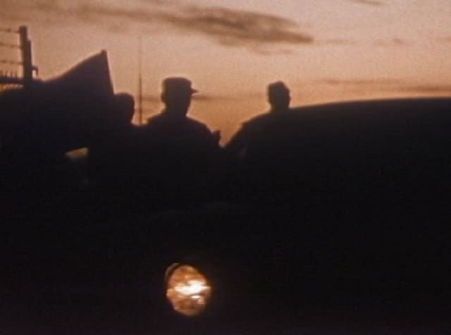 Three figures in silhouette against an orange dusk sky