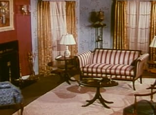 A 1940s living room with a striped sofa and lamps