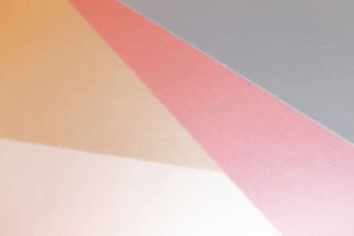 Overlapping sheets of peach, pink and white paper