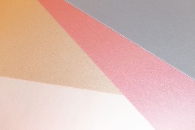 Overlapping sheets of peach, pink and white paper