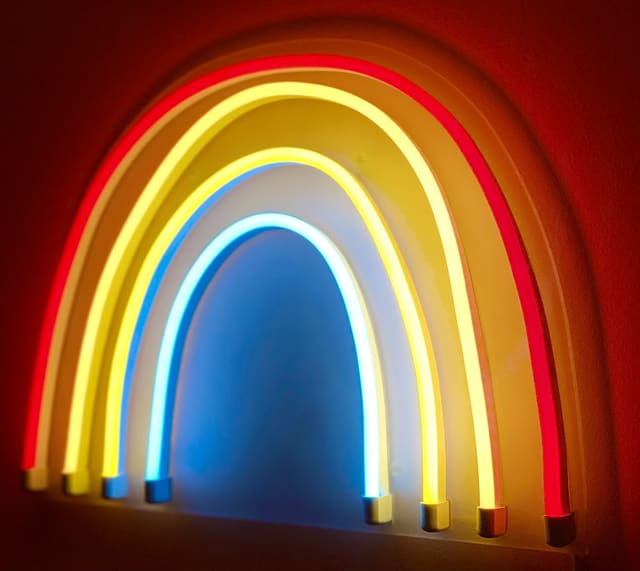 A rainbow-shaped neon light on a dark wall