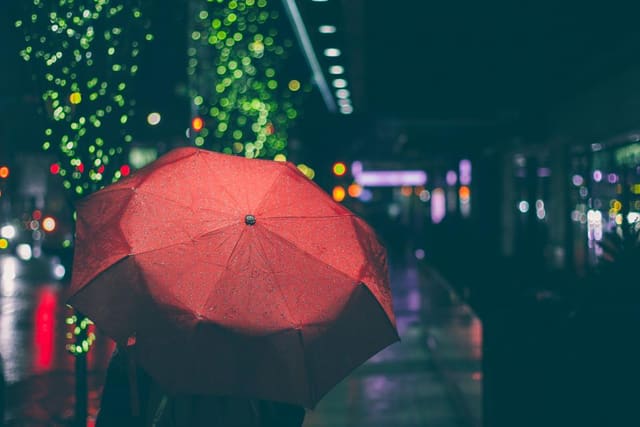 A red umbrella against blurred city lights at night