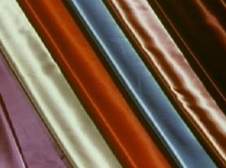 Folds of satin fabric in rust, blue and cream